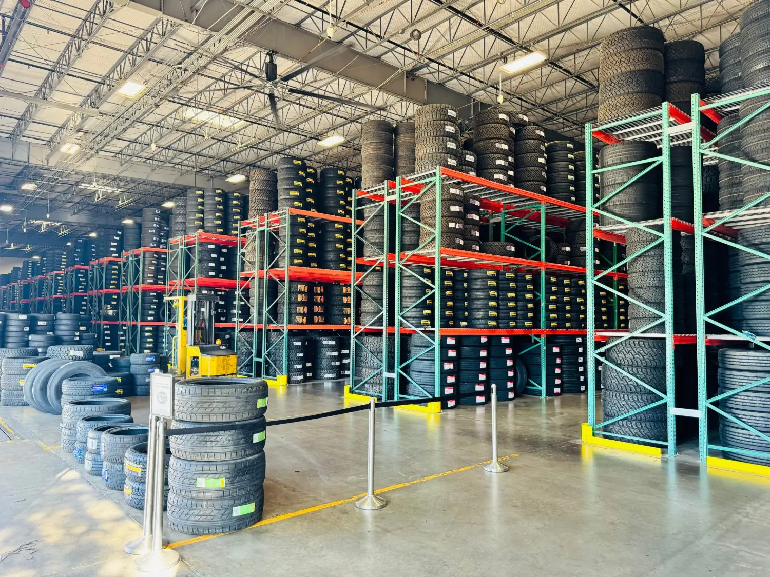 Inside the WTD USA warehouse: tall racks stacked with tires and a forklift on the floor
